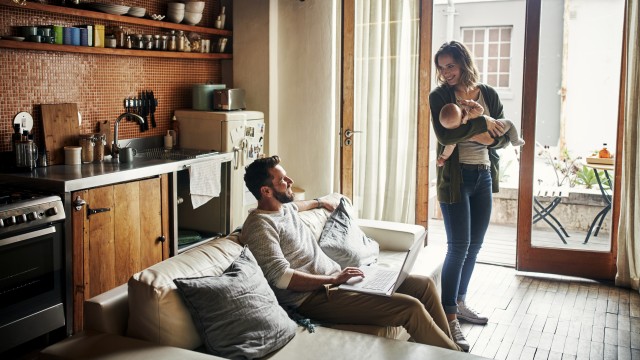 Ein Paar mit Baby freut sich über das Wohnzimmer ihrer neuen Wohnung Ein Paar mit Baby freut sich über das Wohnzimmer ihrer neuen Wohnung