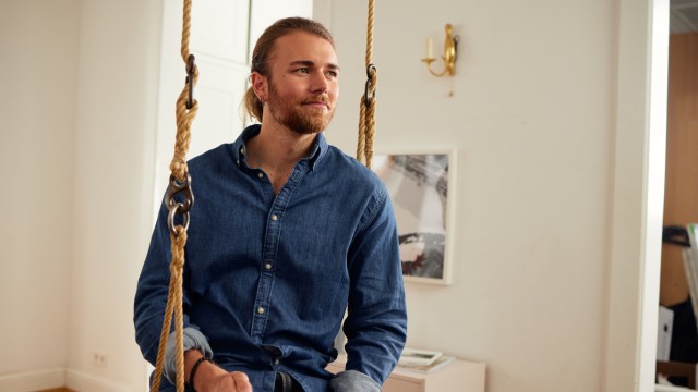 Ein junger Mann sitzt in der Schaukel seines ersten Hauses, welches er mit einem Bausparvetrag finanziert hat Ein junger Mann sitzt in der Schaukel seines ersten Hauses, welches er mit einem Bausparvetrag finanziert hat