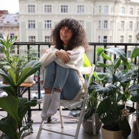 Eine junge Frau sitzt auf dem Balkon ihrer ersten eigenen Wohnung Eine junge Frau sitzt auf dem Balkon ihrer ersten eigenen Wohnung