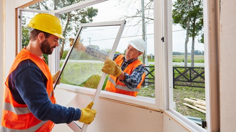 Handwerker bauen im Rahmen einer Sanierung neue Fenster ein Handwerker bauen im Rahmen einer Sanierung neue Fenster ein