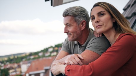 Ein Paar lehnt sich aus dem Fenster Ihrer Wohnung, für welche sie eine Anschlussfinanzierung abgeschlossen haben Ein Paar lehnt sich aus dem Fenster Ihrer Wohnung, für welche sie eine Anschlussfinanzierung abgeschlossen haben