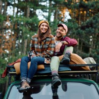 Ein junges Paar sitzt auf dem Dach ihres Campervans Ein junges Paar sitzt auf dem Dach ihres Campervans